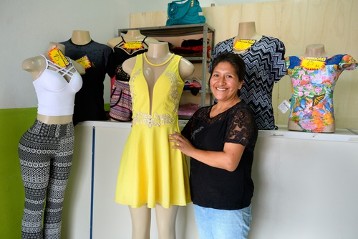 Nancy Salva, 41 Jahre, zeigt stolz ein Festkleid aus ihrer eigenen Kreation, das sie im Laden vor ihrer Schneiderwerkstatt verkauft
