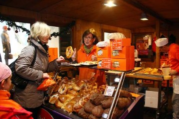Vorne: Verkauf von Adveniat-Brot. Hinten: Bäcker Schmidt von "Bäcker Peter" im Adveniat-Brotbackhaus auf dem Essener Weihnachtsmarkt 2012