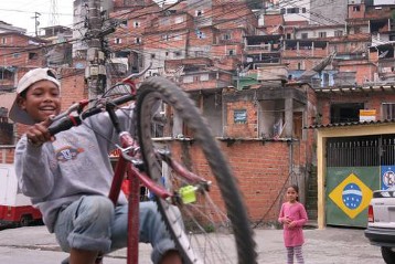 Spielender Junge mit  Fahrrad in einer Favela im Distrikt Brasilandia im Norden von São Paulo
