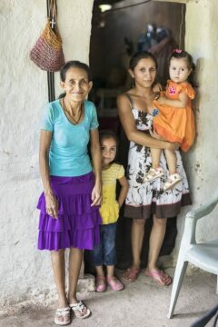Auch Doña Glória (52 Jahre) und ihre Familie (hier mit Schwieger-Tochter Mary Selena Muñoz und 2 Enkelkindern) sind von der Krise betroffen. Vor 40 Jahren haben sie aus der Not heraus Land besetzt. Bis heute können sie daher überleben. Viel ist es nicht, sie leben in extremer Armut. Neben dem fehlenden Land ist die nicht vorhandene Gesundheitsversorgung und Wasser ein Problem: es gibt immer weniger. Was ihr hilft ist ihr fester Glaube. Und Radio Progreso, das sie jeden Morgen hört – auch wenn der örtliche Priester dies verboten hat.