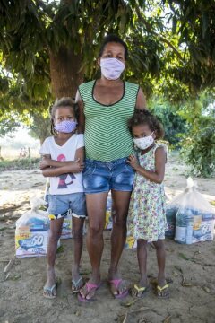 Mutter mit zwei Kindern, alle mit Mund-Nasenschutz. Schwester Neusa do Nascimento und Schwester Leticia verteilen Lebensmittel, Hygieneartikel und Schutzmasken im Rahmen der Corona-Soforthilfe der Fischereipastorale CPP