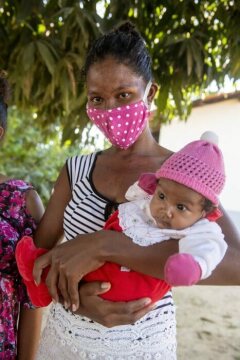 Mutter mit Mund-Nasenschutz und Baby. Schwester Neusa do Nascimento und Schwester Leticia verteilen Lebensmittel, Hygieneartikel und Schutzmasken im Rahmen der Corona-Soforthilfe der Fischereipastorale CPP