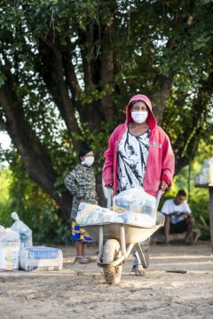 Frau transportiert die erhaltenen Güter mit Schubkarre nach Hause. Schwester Neusa do Nascimento und Schwester Leticia verteilen Lebensmittel, Hygieneartikel und Schutzmasken im Rahmen der Corona-Soforthilfe der Fischereipastorale CPP