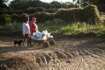 Frauen transportieren die erhaltenen Güter mit Schubkarre nach Hause. Schwester Neusa do Nascimento und Schwester Leticia verteilen Lebensmittel, Hygieneartikel und Schutzmasken im Rahmen der Corona-Soforthilfe der Fischereipastorale CPP