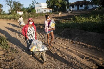Frauen transportieren die erhaltenen Güter mit Schubkarre nach Hause. Schwester Neusa do Nascimento und Schwester Leticia verteilen Lebensmittel, Hygieneartikel und Schutzmasken im Rahmen der Corona-Soforthilfe der Fischereipastorale CPP