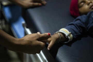 Um ihren Sohn zu beruhigen, hält eine guatemaltekische Mutter während der ärztlichen Untersuchung in der Migrantenherberge "Casa Mambré" seine Hand.