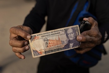 Migranten zeigen venezolanische Banknoten (Bolivar). Die Abwertung war so groß, dass ihr Geld nichts mehr wert ist.