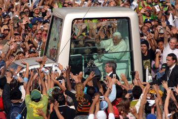 Papst Benedikt bei der Ankunft vor der Basilika in Aparecida am 13. Mai 2007, während seiner Pastoralreise nach Brasilien. Der Papst wird von jubelnden Menschenmassen begrüßt, er winkt aus dem Papamobil den Gläubigen zu.